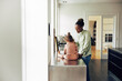 © Flamingo Images - Mom standing her kitchen with her little girl sitting on a counter