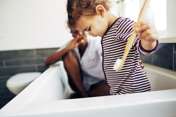 Wall Mural - Little girl with a toothbrush sitting with her mom in their bathroom