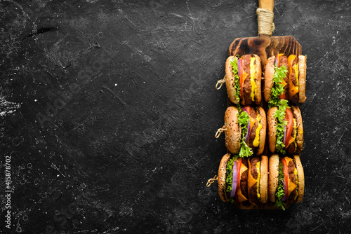 Homemade hamburger with fresh vegetables, meat and cheese. Top view. On a black stone background. © Yaruniv-Studio