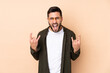 © luismolinero - Caucasian handsome man isolated on beige background making horn gesture
