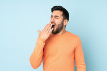 Caucasian Handsome Man Yawning And Covering Wide Open Mouth With Hand Over Isolated Blue Background