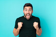© luismolinero - Caucasian handsome man isolated on blue background celebrating a victory in winner position