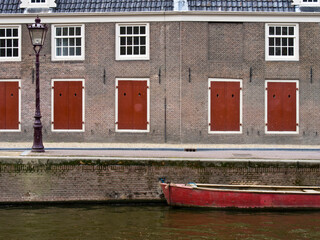 Sticker - Netherlands, Amsterdam. Colorful red doors along the canal with a red boat.