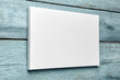 © mikeosphoto - Canvas hanging on light blue wooden wall, white canvas print mockup