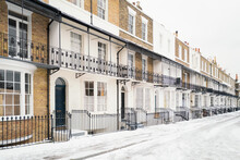 Georgian Or Victorian Style Terrace Houses Other Wise Known As Row Houses In The Snow In Winter. They Have Ornate Railings And Basements