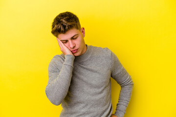 Young caucasian man isolated on yellow background who is bored, fatigued and need a relax day.