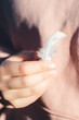 © manuta - Light white feather in young girl hands, pink background, Health And Body Care Concepts