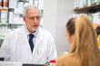 © Minerva Studio - Pharmacist serving a female customer in his pharmacy