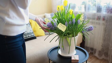 Wall Mural - Woman smells blooming spring yellow flowers with greeting card at home. International Womens Day, 8 March present. Gift for holiday with 2021 colors