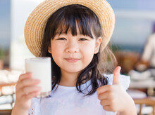 Fresh Organic Lactose Free Milk On Glass.Asian Cute Little Girl Drinking Milk.Calcium Vitamin From Milk.Grocery Food.Good Taste.Kid Drink Goat Milk.School Kid Girl Wearing Straw Hat.Delicious Tasty.