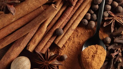 Wall Mural - close up of various spices rotating on wooden table top view