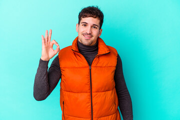 Wall Mural - Young caucasian man isolated on blue background cheerful and confident showing ok gesture.