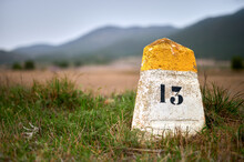 Milestone Or Milepost Sign On A Rural Road With Hills In The Bac