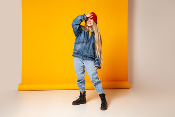 Wall Mural - Cheerful trendy woman in denim outfit and hat having fun in studio