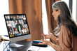 © Kateryna - Virtual meeting, online business meeting. Asian adult gray-haired woman communicating with business coworkers via video call uses app and computer, sitting at her work desk