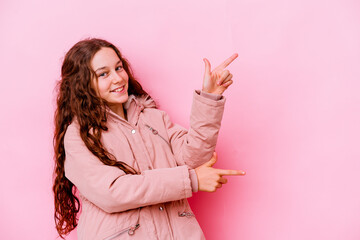 Little caucasian girl isolated on pink background excited pointing with forefingers away.