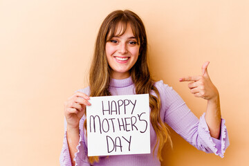 Wall Mural - Young caucasian woman holding a Happy mothers day placard isolated person pointing by hand to a shirt copy space, proud and confident