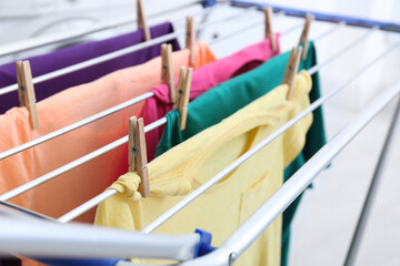 Clean laundry hanging on drying rack indoors, closeup