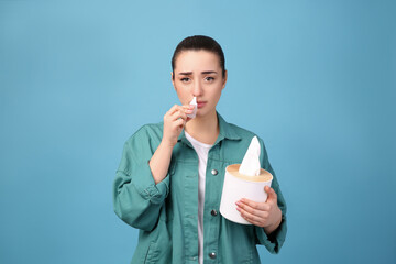 Canvas Print - Woman using nasal spray on light blue background