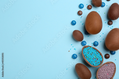 Obraz Dibond Sweet chocolate eggs and candies on light blue background, flat lay. Space for text