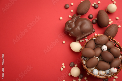 Obraz Dibond Flat lay composition with chocolate Easter bunny, eggs and candies on red background. Space for text