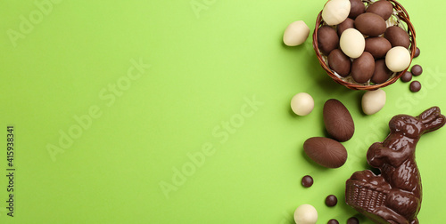 Obraz Dibond Flat lay composition with chocolate Easter bunny, eggs and candies on green background. Space for text