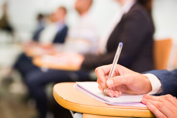 Cropped view of businessman hand making notes during business event in conference hall