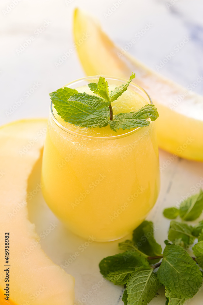 Glass with melon smoothie with mint on light background