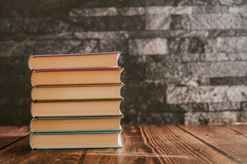 Wall Mural - Stack of books in the colored cover lay on the wood table  with dark backround. Education learning concept