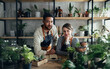 © Halfpoint - Shop assistants looking at camera in indoor potted plant store, small business concept.