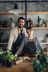 Shop assistants looking at camera in indoor potted plant store, small business concept.