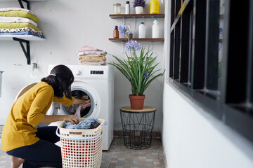 Wall Mural - woman in front of the washing machine doing some laundry loading clothes inside