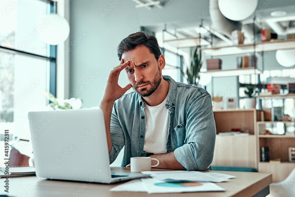 Thoughtful businessman looking at laptop screen - obrazy, fototapety, plakaty 