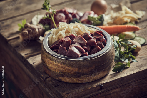 Bowl with fresh cut meat with cartilages and healthy veggies scattered on table © exclusive-design