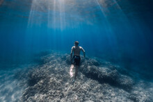 Male Free Diver Glides Underwater In Clear Ocean In Hawaii