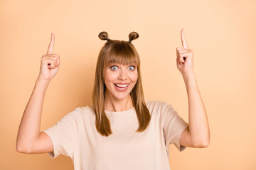 Poster - Photo portrait of funny girl pointing up fingers blank space recommending staring isolated on pastel beige color background