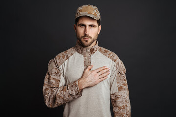 Wall Mural - Confident masculine military man holding hand on his chest