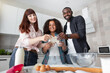 © sofiko14 - Multiethnic family looking at the camera while holding dough for pizza, muffins or cookies
