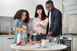 © sofiko14 - Family baking pastry or pie at home. Caucasian mom and mixed race daughter, sifting flour by sieve, while happy handsome african father helping with smile