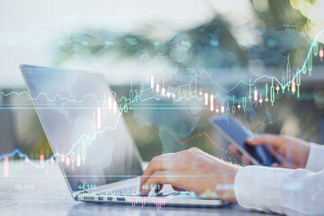 Poster - Online investment concept: digital screen with stock market diagram and graphs and man using laptop and smartphone at background