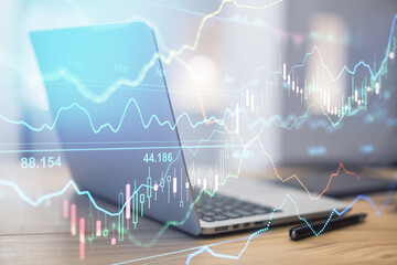 Poster - Online stock market concept with transparent digital screen with financial graphs and opened laptop on wooden table at background