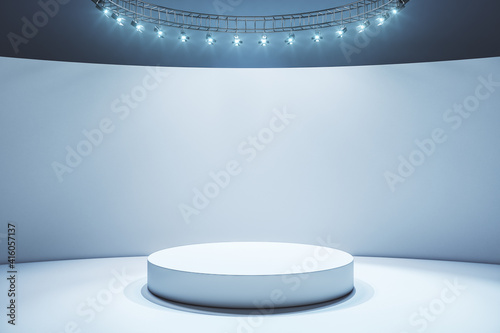 White round podium in empty stylish hall with light wall and floor and led lights on top © peshkov