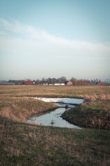 Wall Mural - Small stream of water with snow smelting in cold farmland landscape in southern Sweden