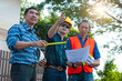© Wasan - The construction project inspector team visits the site to inspect the construction site. Engineers and contractors hold the plan and point it at the structure of the building.