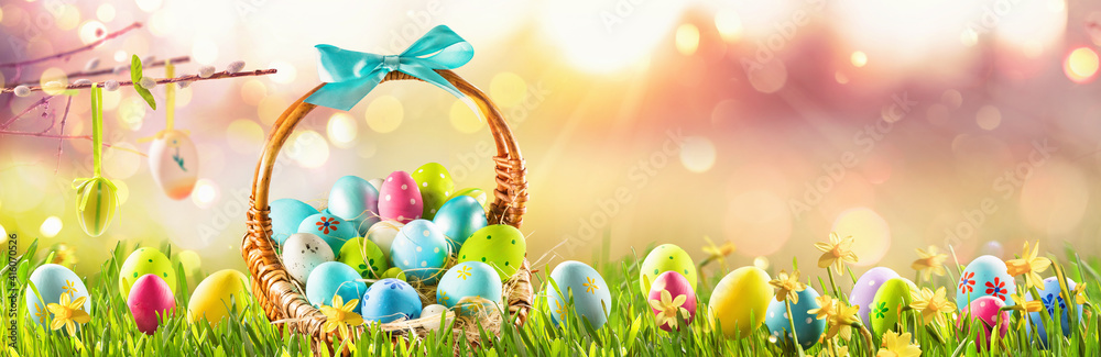 Easter Eggs in a Basket on Green Grass Sunny Background - obrazy, fototapety, plakaty 