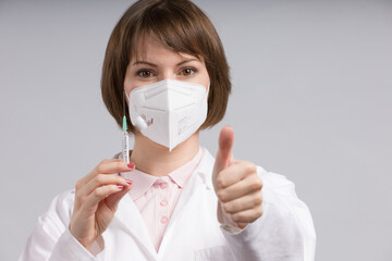 Wall Mural - female doctor or nurse with syringe pulled up with a vaccination serum shows thumbs up