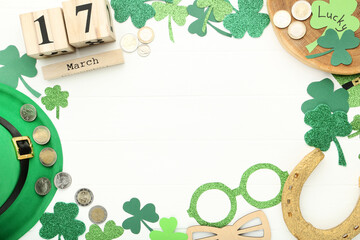 St.Patrick's Day. Paper clover leafs with hat, coins, horseshoe and calendar on white wooden table