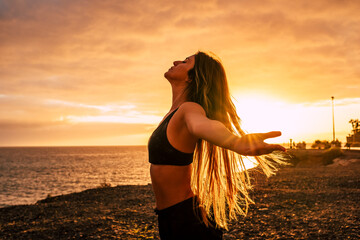 Fitness happy and free young woman enjoy the sunset after the sport workout activity session taking breathe - body health care people concept with beautiful woman outdoor opening arms