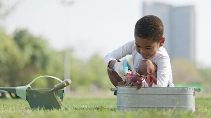 African American boy planted a tree in garden. And planting equipment. Family activities during summer holidays. Kid learn to protect environment And natural growth. Concept Take Care environmental