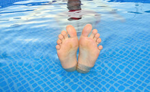 Close-up - Male Feet In Blue Clear Water Of The Pool